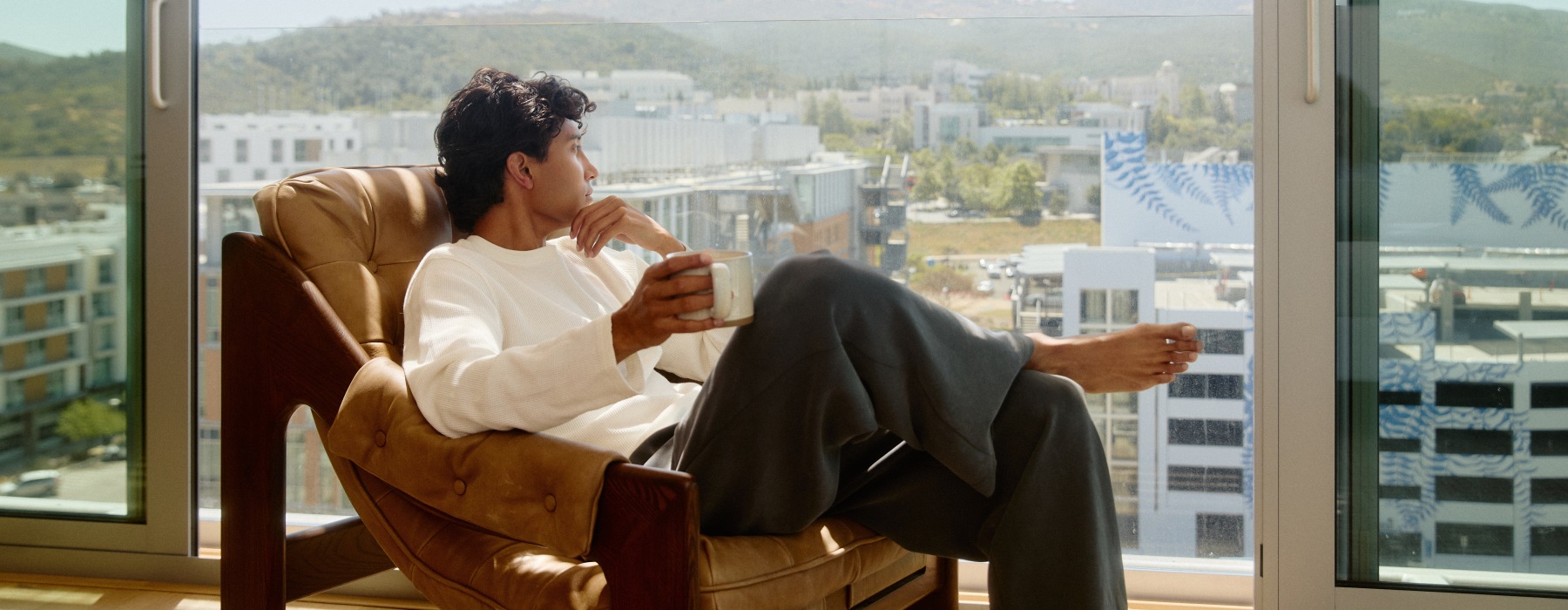 man sitting in a chair looking out a window