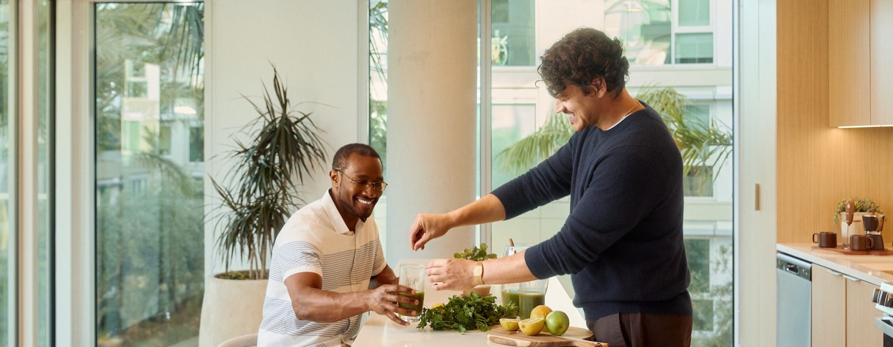 friends making drinks in a kitchen with large windows